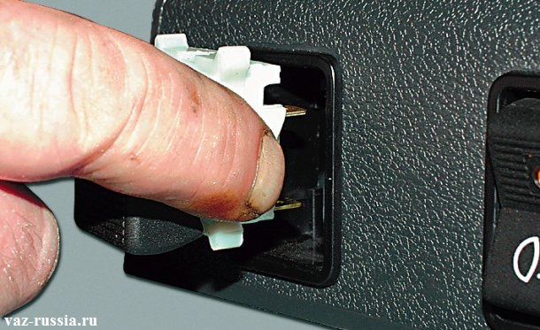 Вставление выключателя в отверстие зажимая при этом его боковые защелки